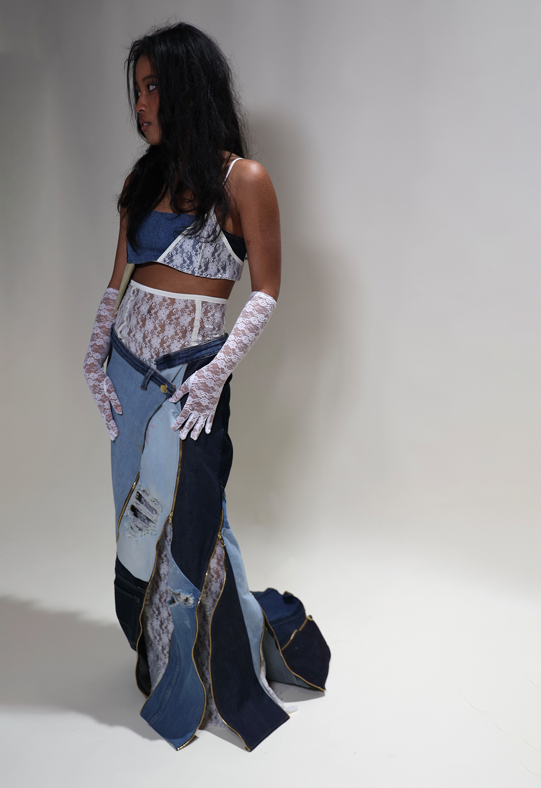 3/4 view of entire look that consists of upcycled denim skirt and bra accompanied with lace and gold zippers.