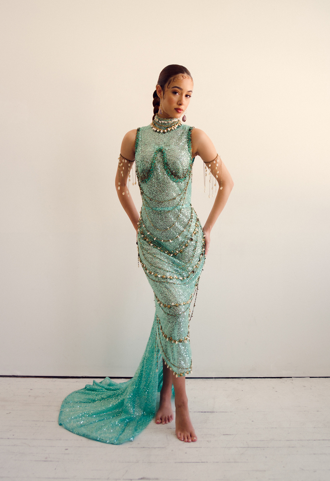 Front view of a model wearing a turquoise beaded dress. The background is white. 