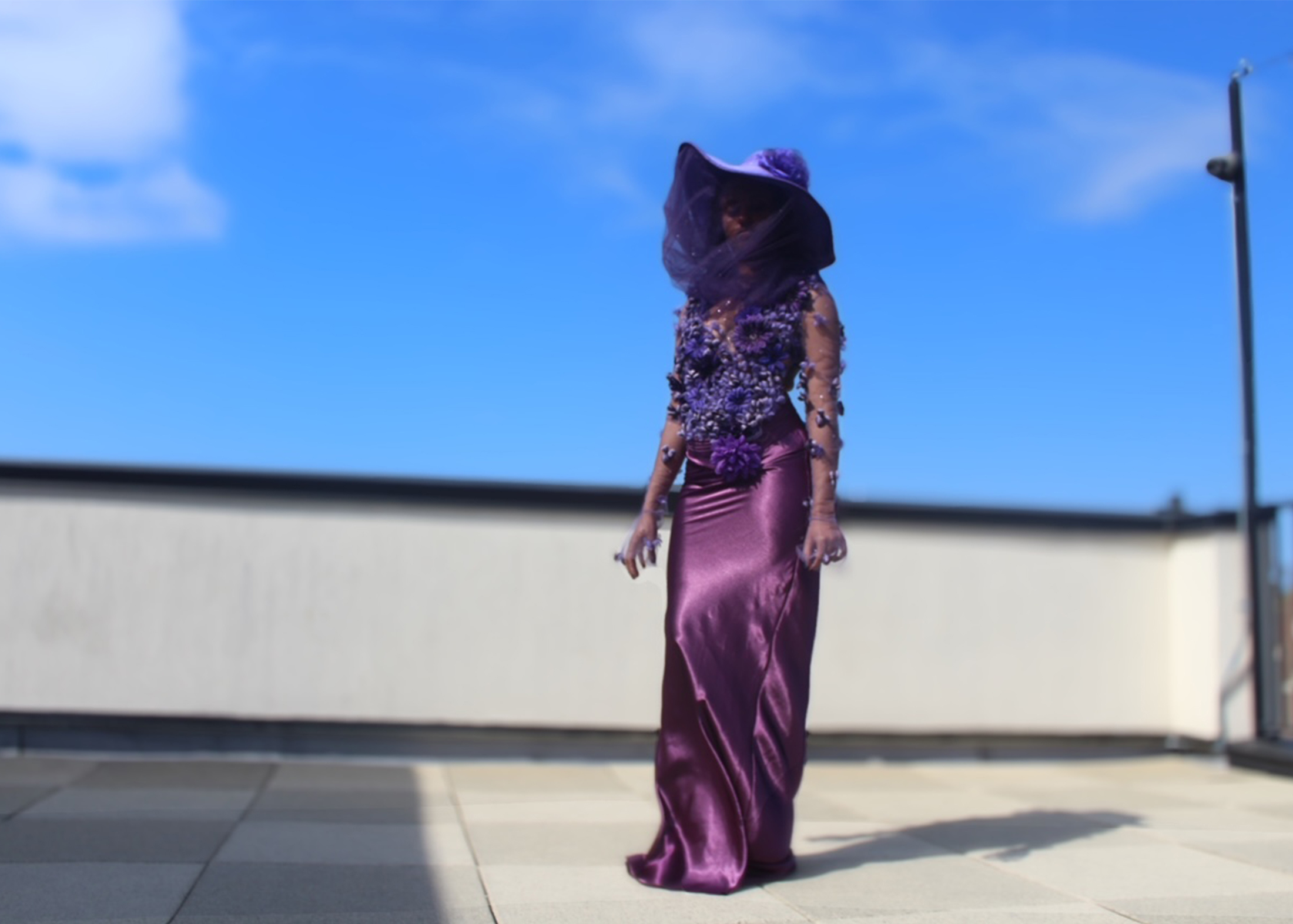 Model in 3D floral amethyst bodysuit, accompanied with a violet charmeuse bias-cut skirt. Model is overlooking Brooklyn, New York, as she poses.