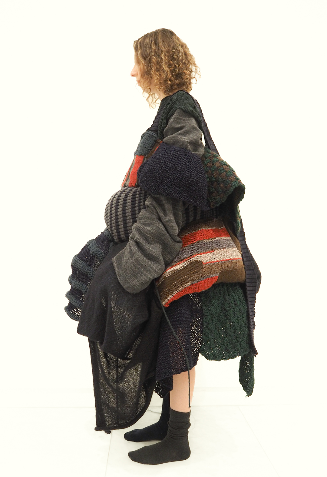 The photo shows a side view of a model wearing a patchwork deconstructed bustle dress with an oversized sleeve top.