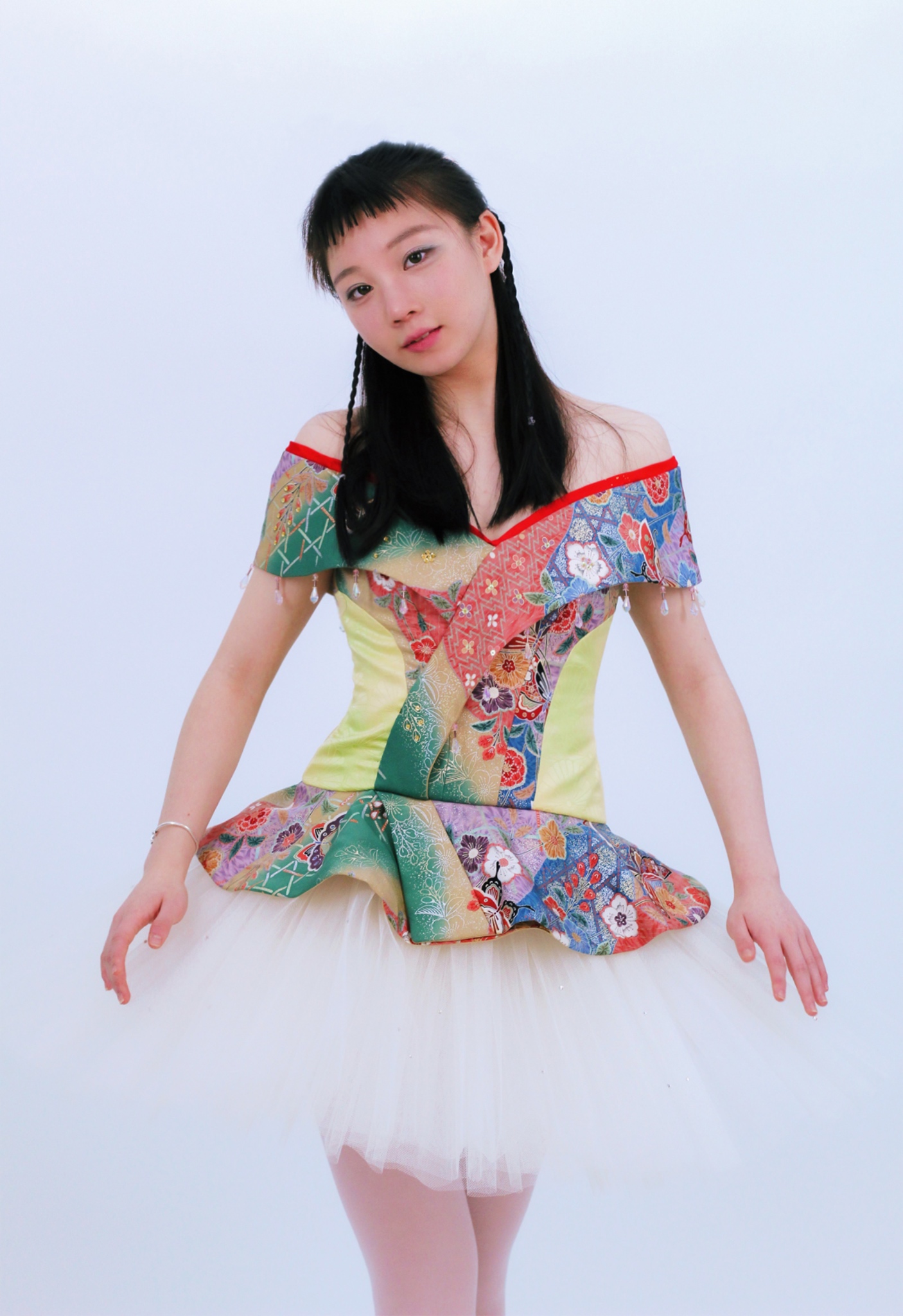 A kimono-inspired silk printed bodice top with classical ballet tulle tutu. The photo shows a full view of a ballerina looking into the camera. She is facing front with her hands off to the side.