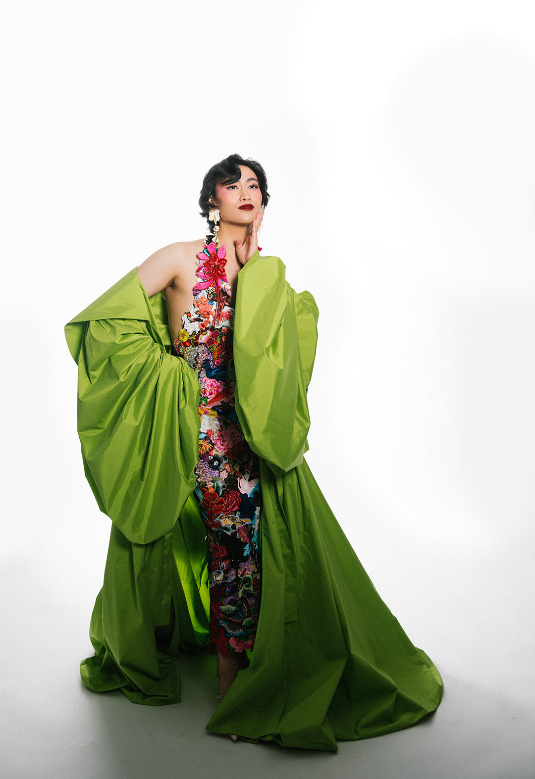 The model is wearing an opera coat in spring-green taffeta and underneath is a halter dress made of embroidery patches, appliqués, and recycled lace collaged and hand-sewn together.