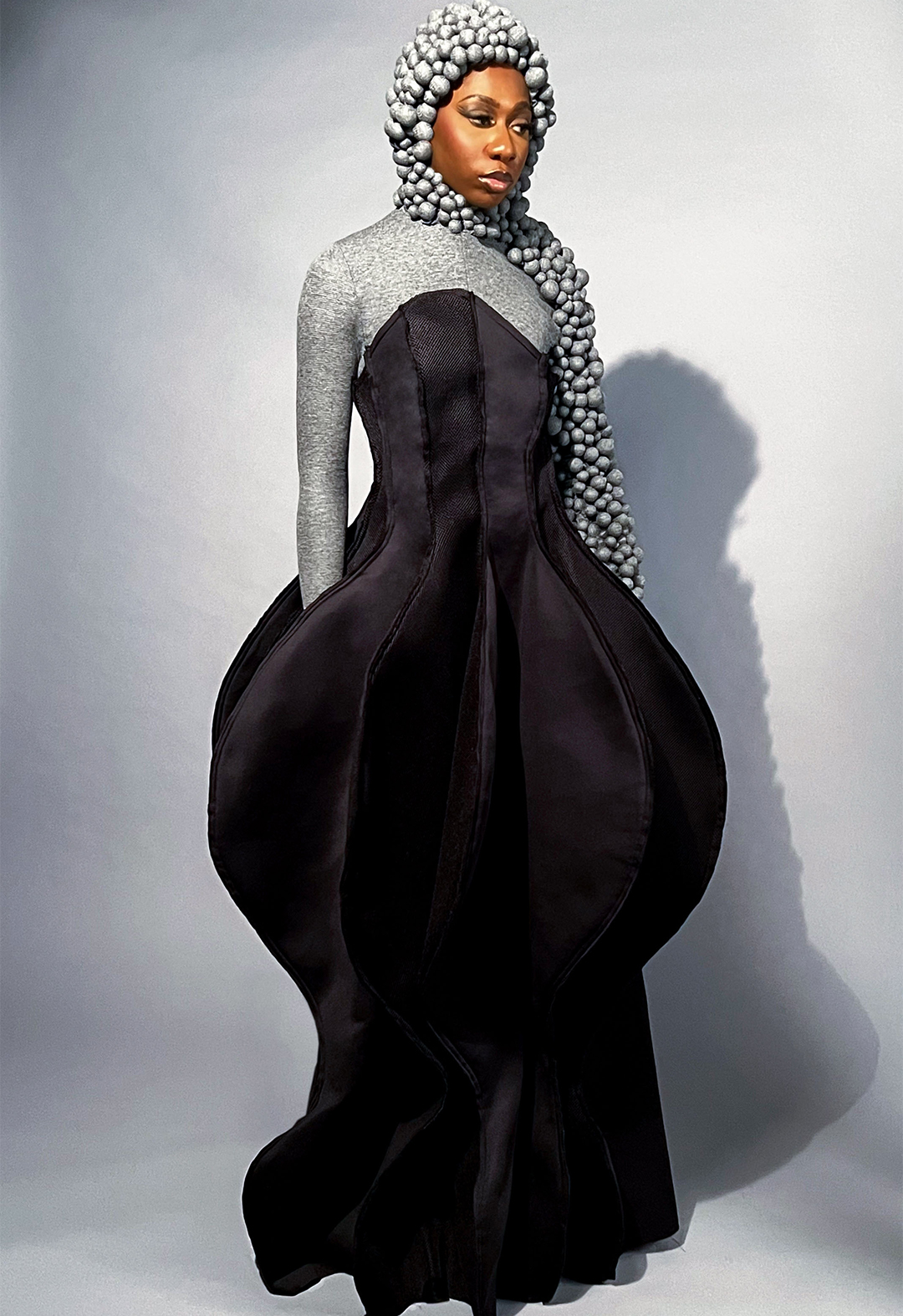 The photo shows a black neoprene and netting three-dimensional sculpted dress over a gray bubble scuba suit.