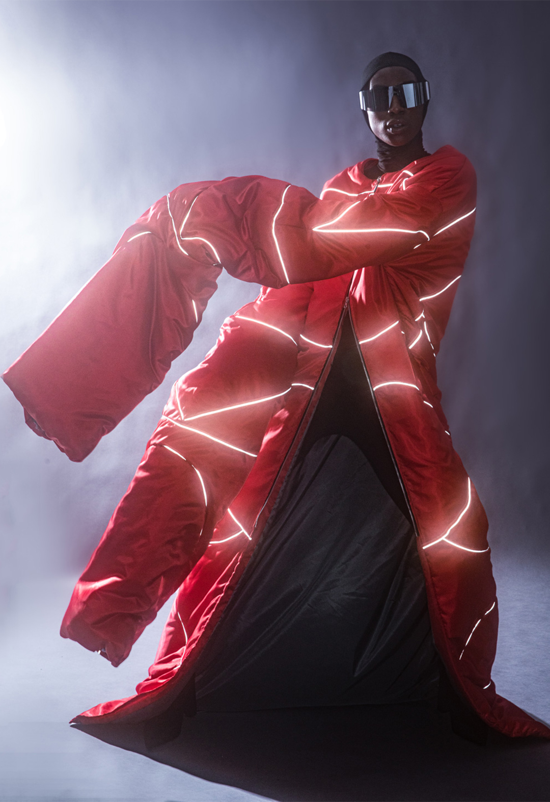 A long bright red coat that shines with reflective piping and a balaclava makes it into an executed piece. 