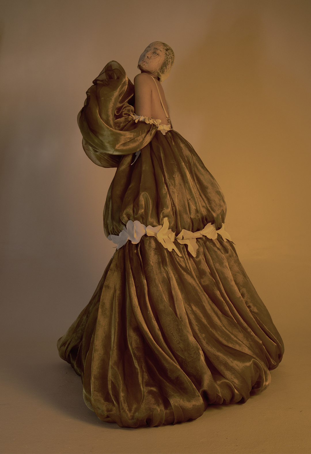Photo shows the model standing sideways to the camera. The sleeves are away from the side, showing a voluminous, bubble-shaped organza gown from the side.