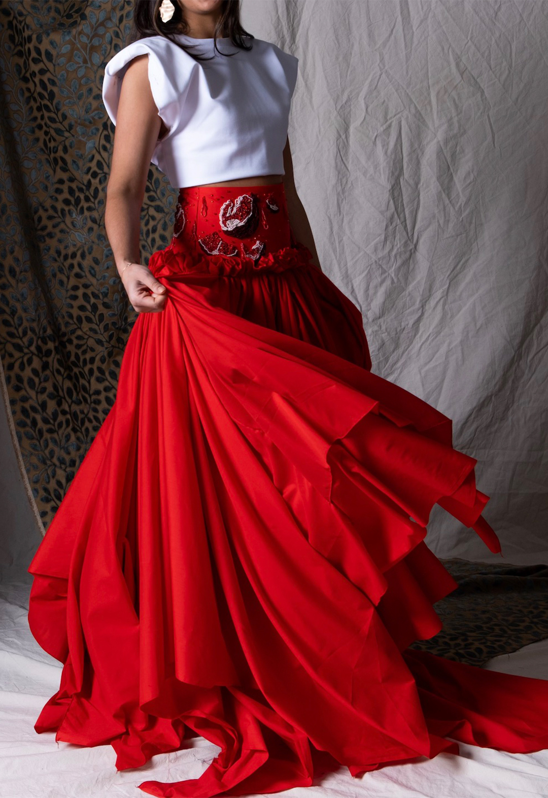 Ani wears a compact ponte T-shirt with structured shoulders, paired with a handkerchief skirt with hand-beaded pomegranates on a drop-waisted yoke. 