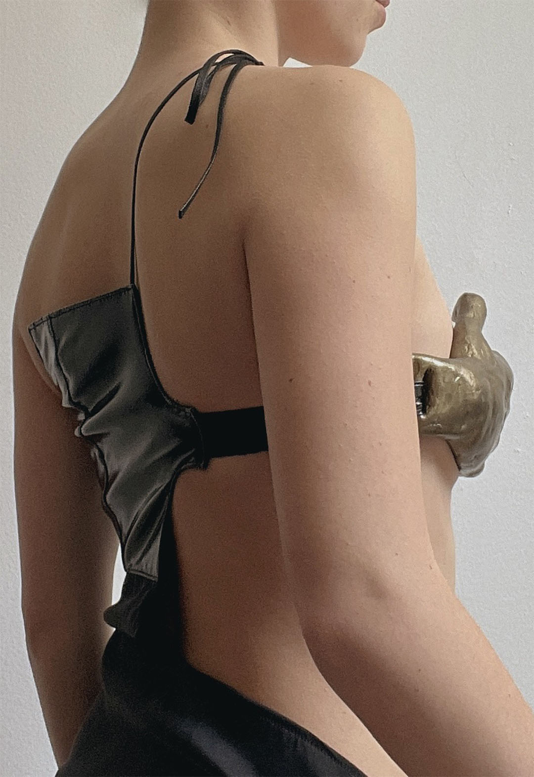 Close up of a girl showing her back at a three-quarter view. She is wearing the dress described previously with the cutout side closest to the camera.