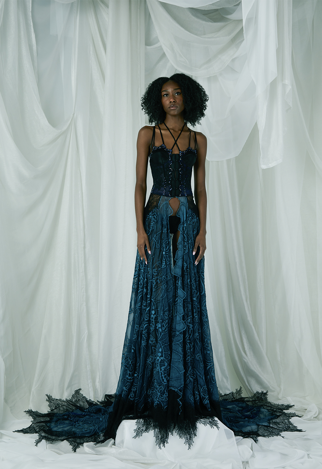 The corset is electric blue, with black lace, criss-crossed bra straps, and crystals. The skirt is blue with embroidered butterflies, crystals, and black lace appliqué hem.