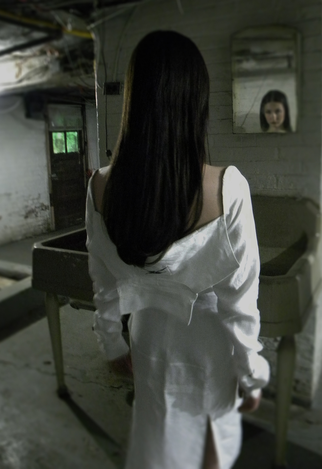 Back view of a model looking into a mirror. She is wearing a white linen shirt dress.