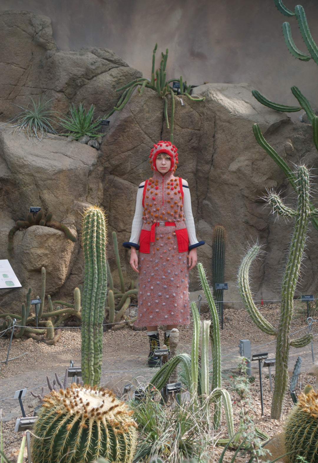 Far away image of a woman in a bobble knit dress standing in a desert landscape.