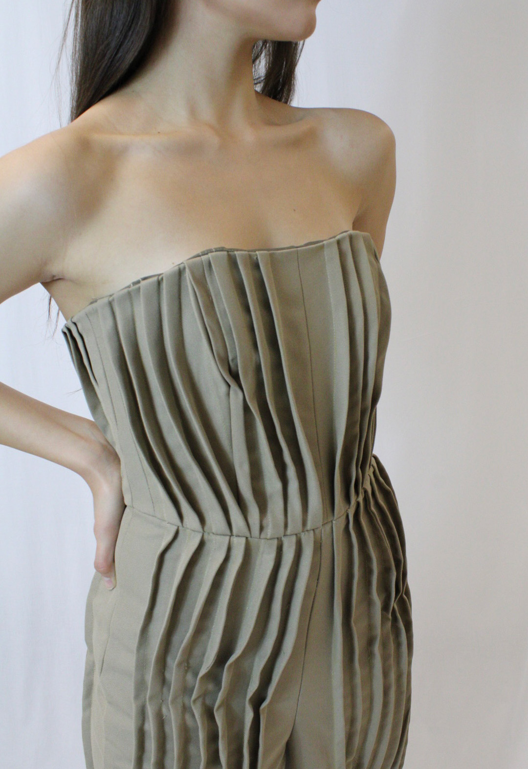 This is a detailed shot of a pleated strapless fitted jumpsuit. The pleats are stitched down to give structure and shape.