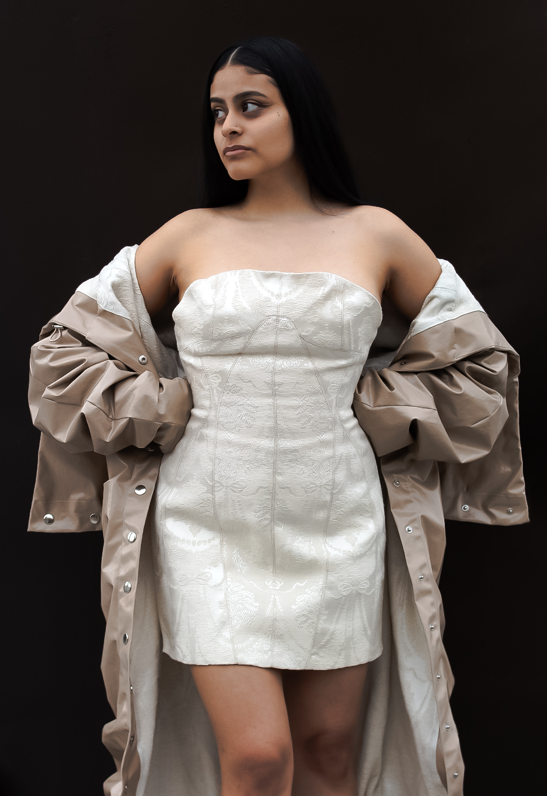 The model is wearing an upholstery jacquard strapless dress with detailed seams and topstitch; the dress matches the coat’s lining.