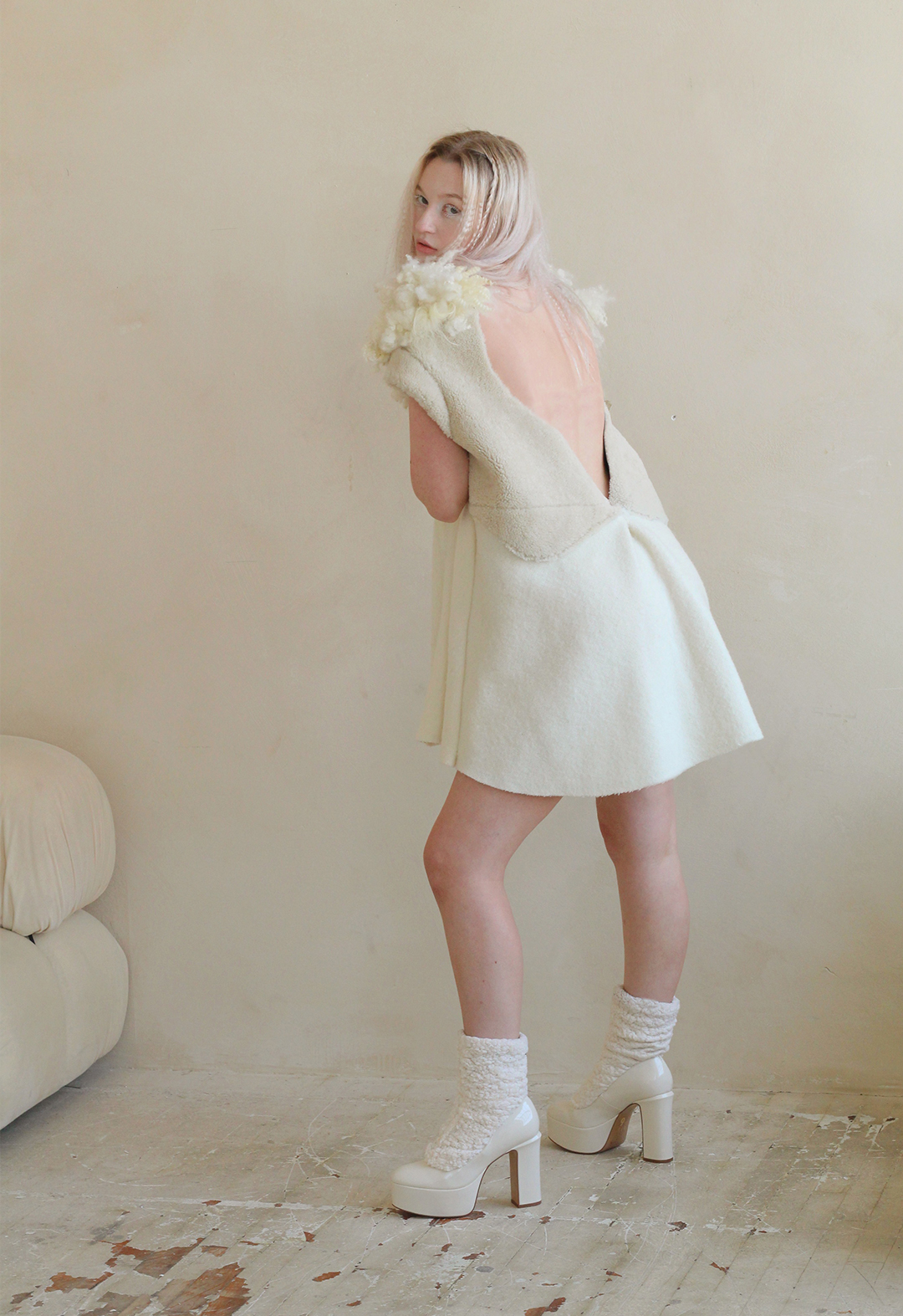 Back view of the model in a mini dress with shearling panel on repurposed wool baby blanket material. 