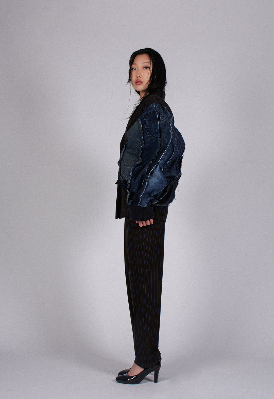 A model posed in a side view of the jacket and suit. The shape of the oversized vintage denim sleeve changes with movement, suggesting that memories and self-fulfillment can be variable. 