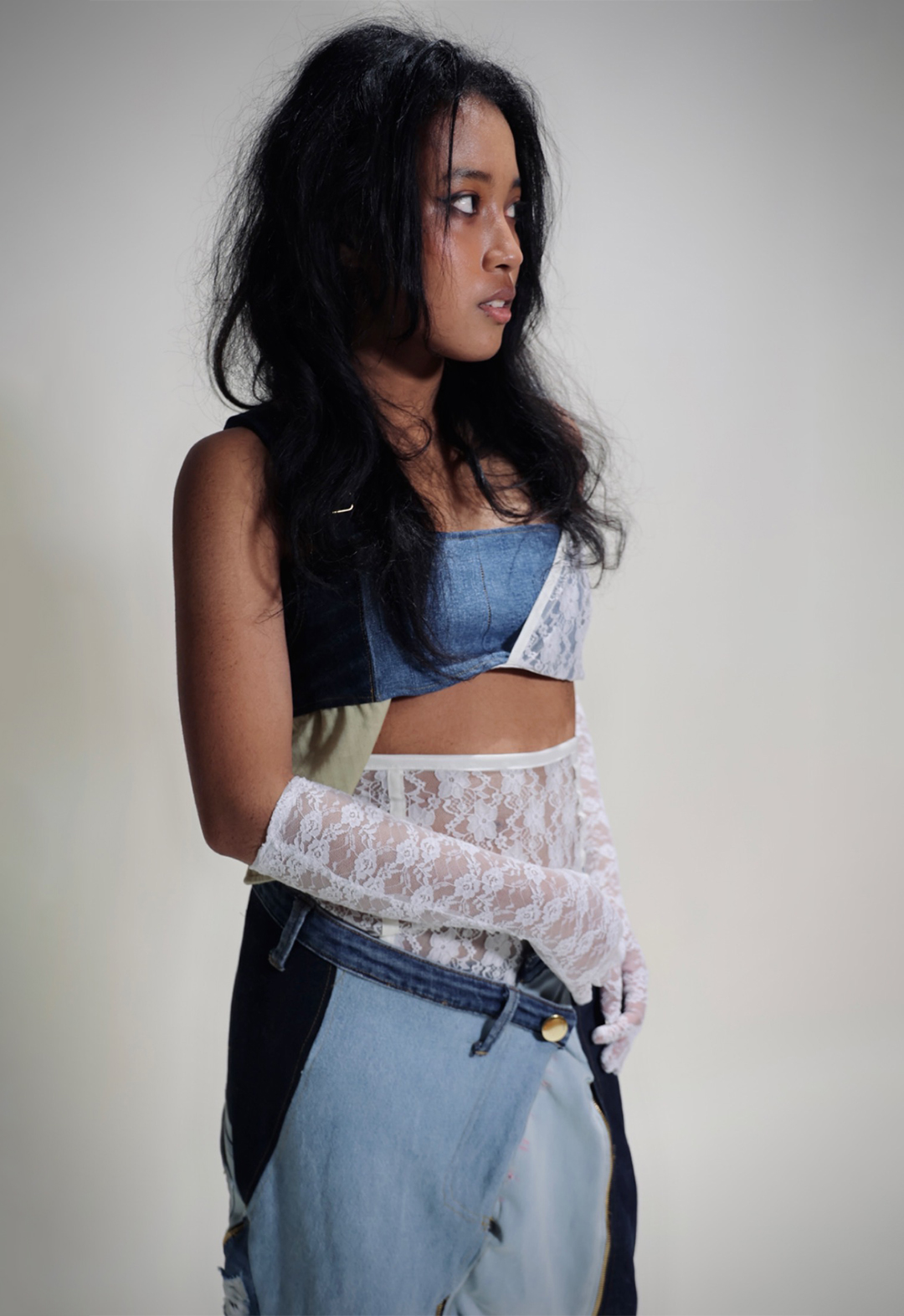 Close up shot of the top half of look consisting of the denim bra, denim skirt and lace underskirt.