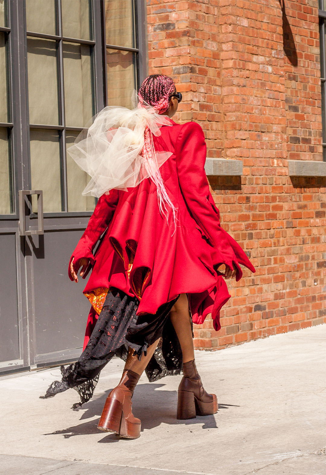 The motion of the draped back of the coat is shown from a different viewers perspective. The lining of the coat peaks out from the hem of the garment. The tulle hair tie is layered to give a smokey look through Traci's hair.