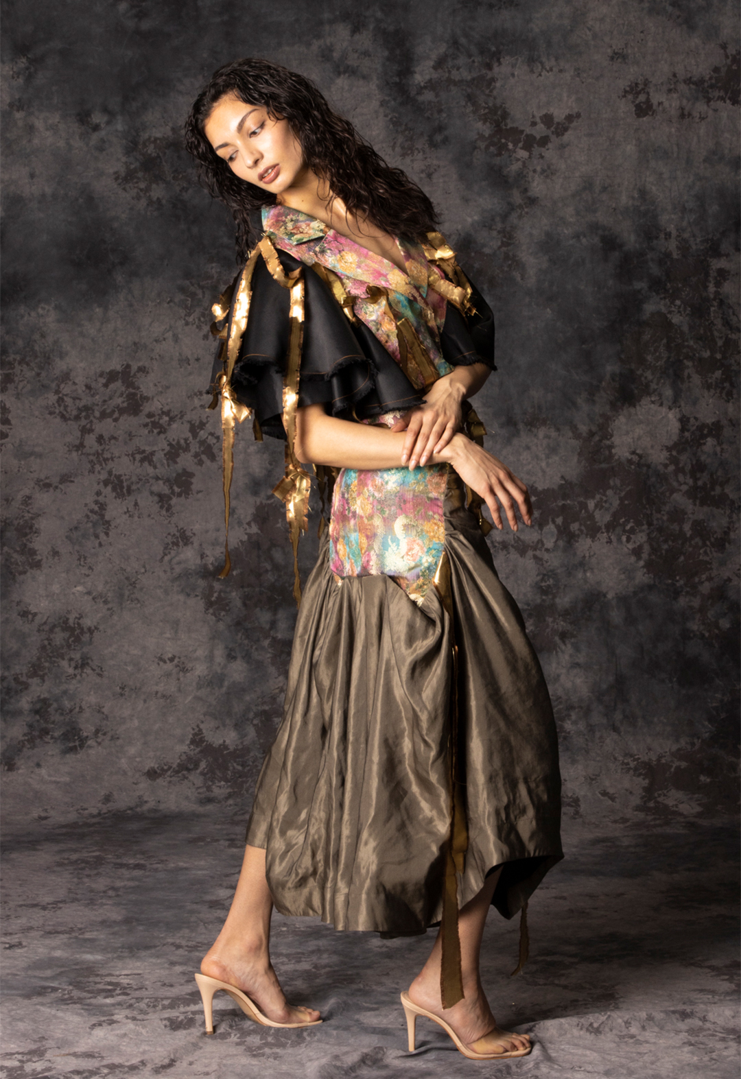 The gentle natural oriental print features a delightful color palette of soft pinks, sunny yellows, rich golds, and verdant greens. The luxurious brocade fabric of the print is elegantly set off by the understated black faille, whose soft draping and balanced sleeves create a harmonious contrast. The decorative gold frayed straps are a striking embellishment, adding a touch of glamour to the ensemble. The brocade is carried over to the skirt, where it appears on both side panels, creating a balanced and coordinated look. The ruched and gathered middle of the skirt creates volume and movement, adding to the drama of the design. The skirt is fully lined with a smooth black polyester fabric, and the waistband is neatly finished with a 1 1/2-inch top stitch for a professional touch.