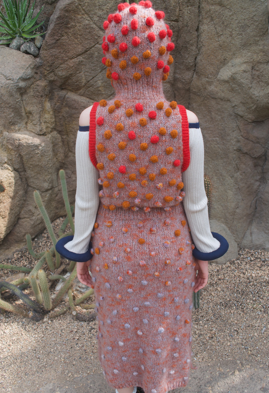 Back view of a woman in a hooded bobble knit dress.