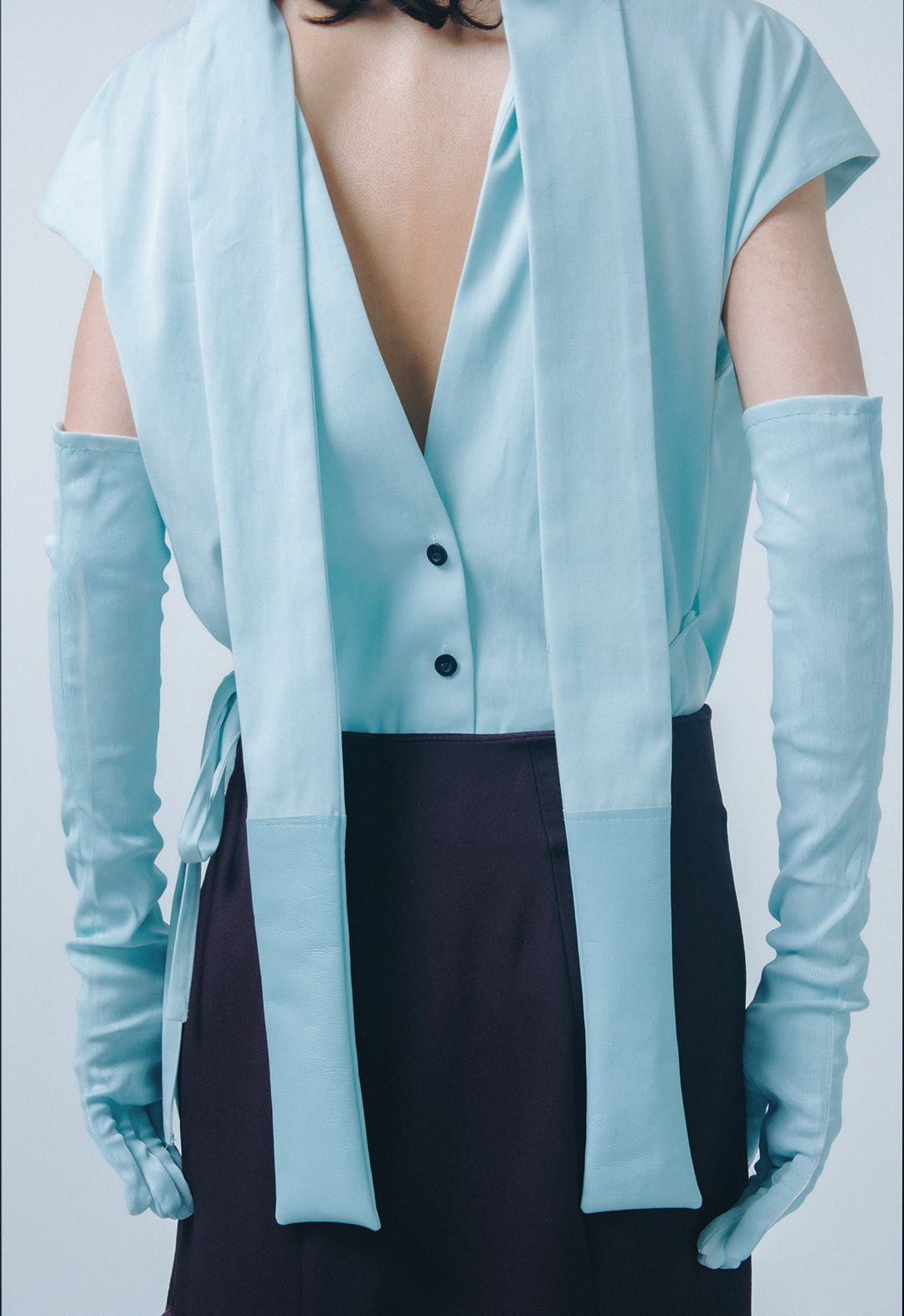 Back view of look 1, showing a baby-blue shirt with overlap collar and back cutout.