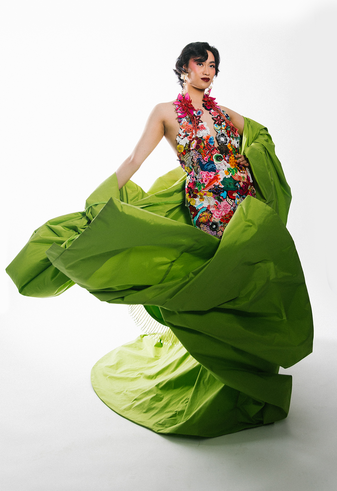 This is another image showing the model in both the collaged halter dress and spring-green taffeta opera coat. The model is in dramatic motion.