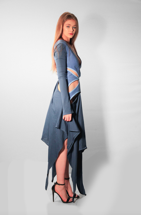 Side view of model wearing blue jersey long sleeve dress, with piped cut-out detail on a brushed cotton bodice.