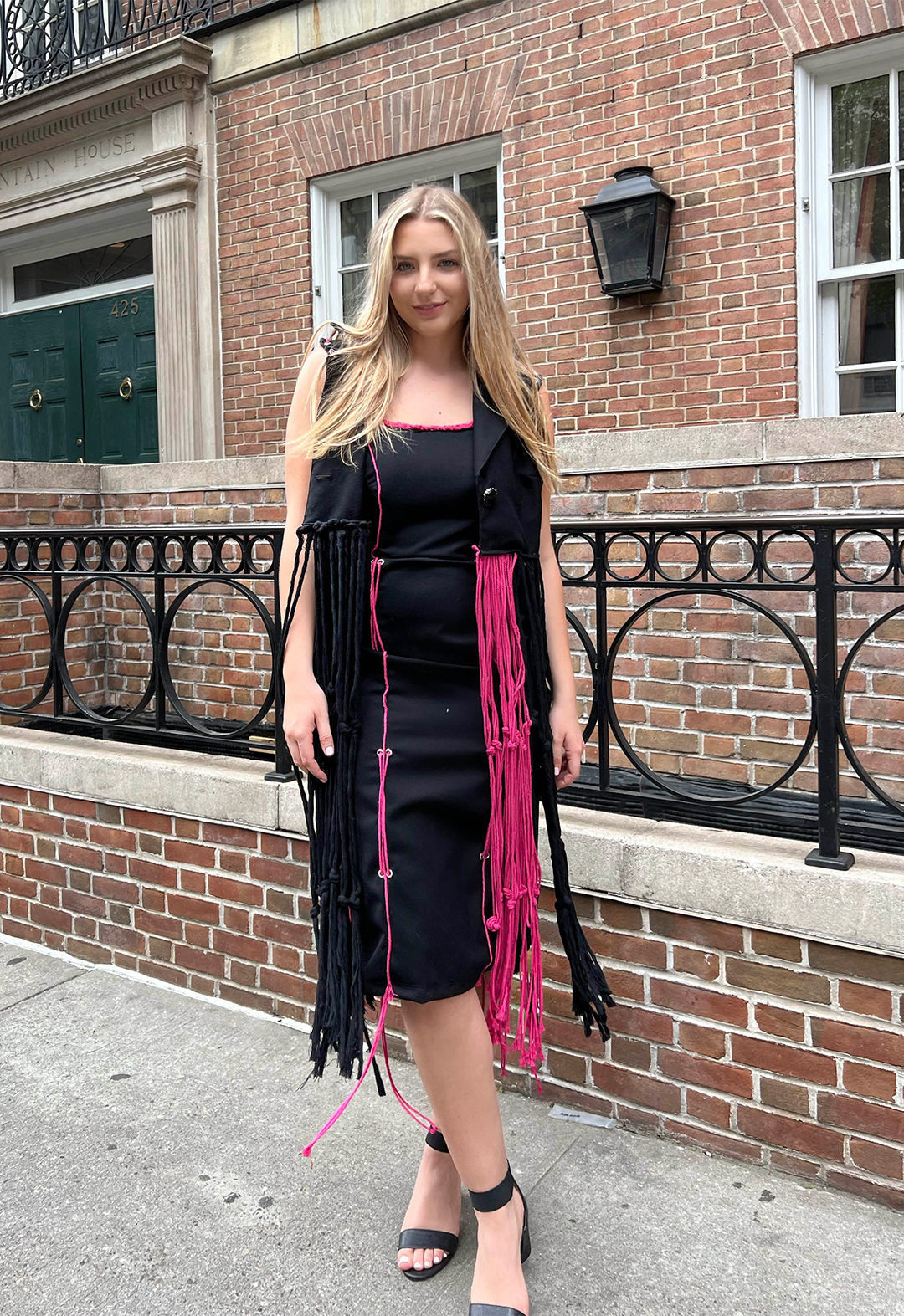A model wears a midi dress and a vest blazer with macramé roping.