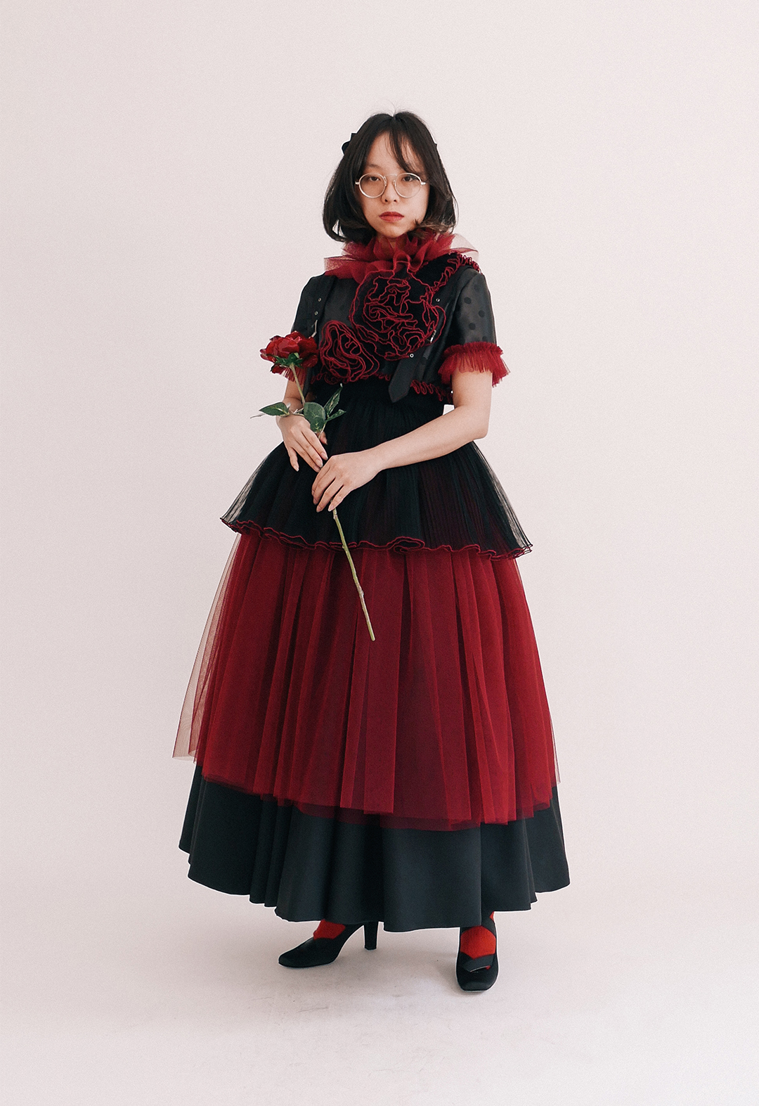 A front view of a model wearing the whole look and holding a resin rose.