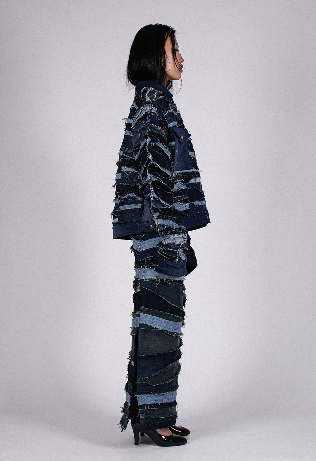 The photo shows a side view of the model in the "Trucker" jacket. The vintage denim in the jacket has different textures and colors, and ultimately, each piece makes a new color and texture.