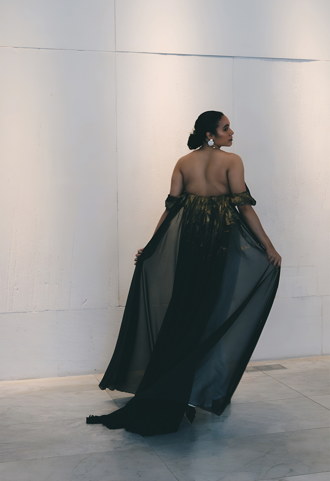 Image of the back of the model wearing a flowing navy blue chiffon train with hand-painted gold accents.