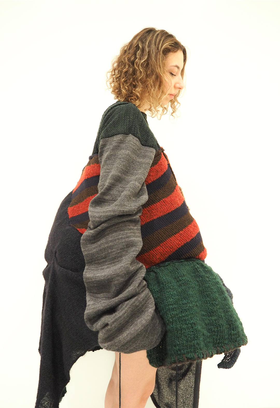 The photo shows a side view of a distorted patchwork dress and the construction of a pleated oversized sleeve. 