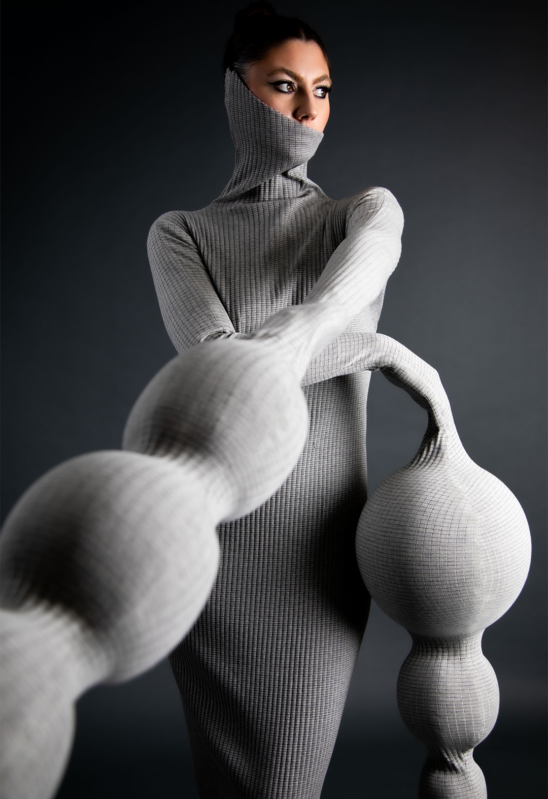 A model is wearing a heather-gray, ribbed spherical dress..