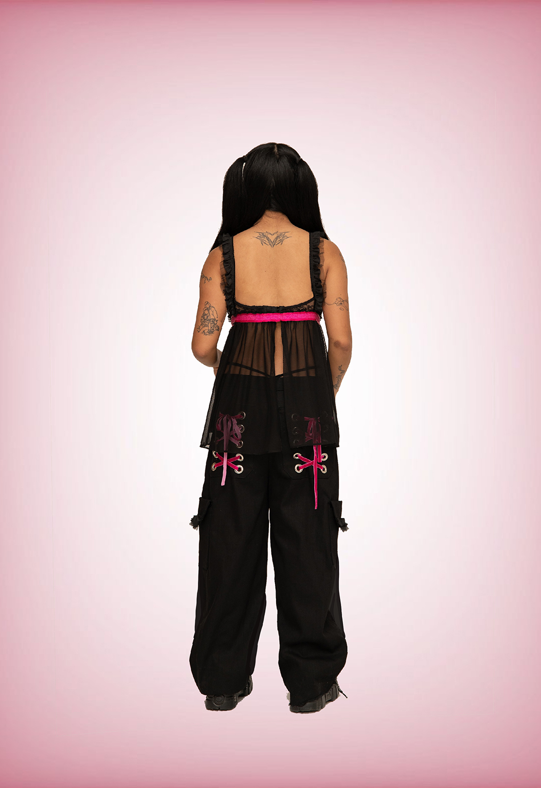 This is a back view image of me modeling the top and pants against a faded pink-and-white background. 