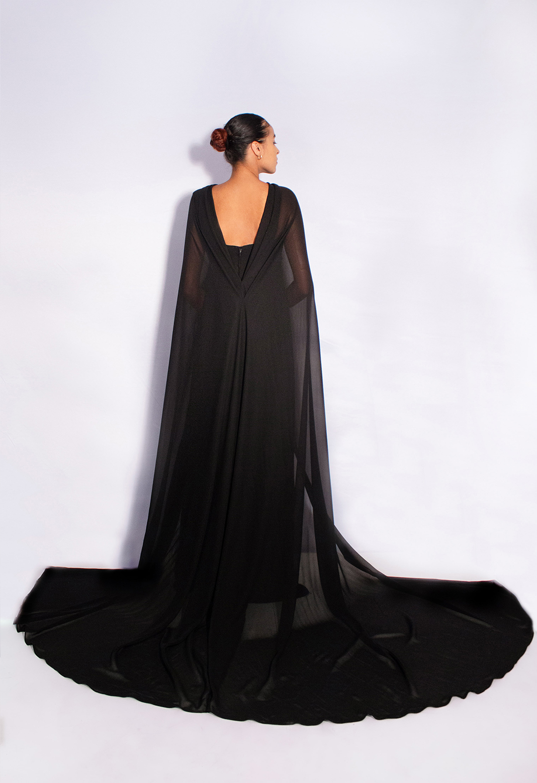 The back view of the dress with a cape. We are able to see a huge portion of the cape, which consists of a double pleat at the back that starts from the shoulder and a long train that is finished with a baby hem. 