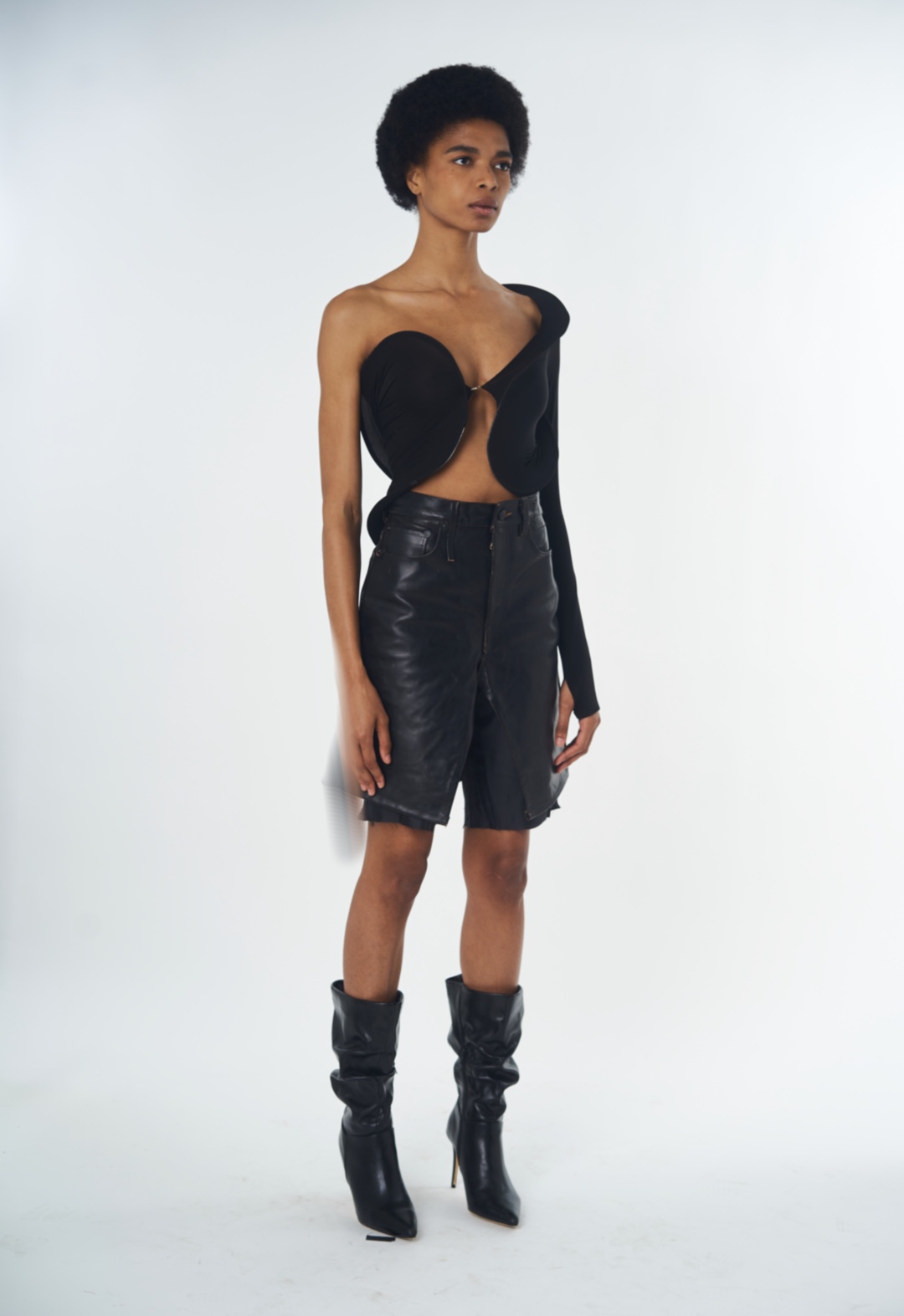 A model wears a sculpted aeriforme top in black with a reworked leather skort. 