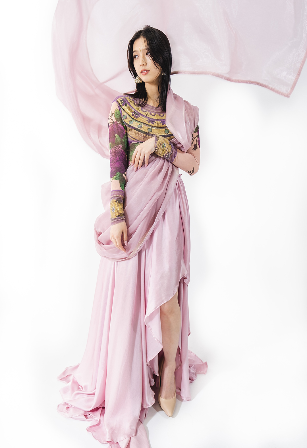 This shot is a sneak peek of the complete look of the dress, with the skirt and its high and low hems, the beautiful organza wrap, and the custom-printed bodysuit with the 3D-printed neckpiece. The overall appearance portrays a contemporary take on the traditional Indian saree.