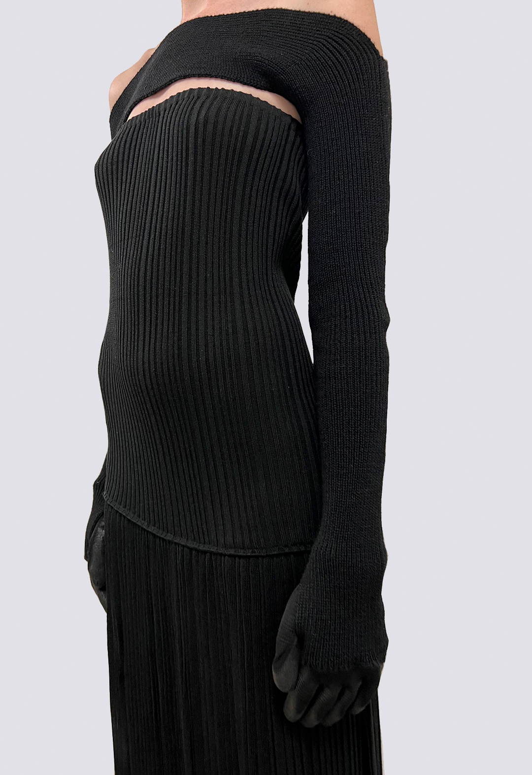 Close-up of black knit top featuring gloves at the end of the sleeve.