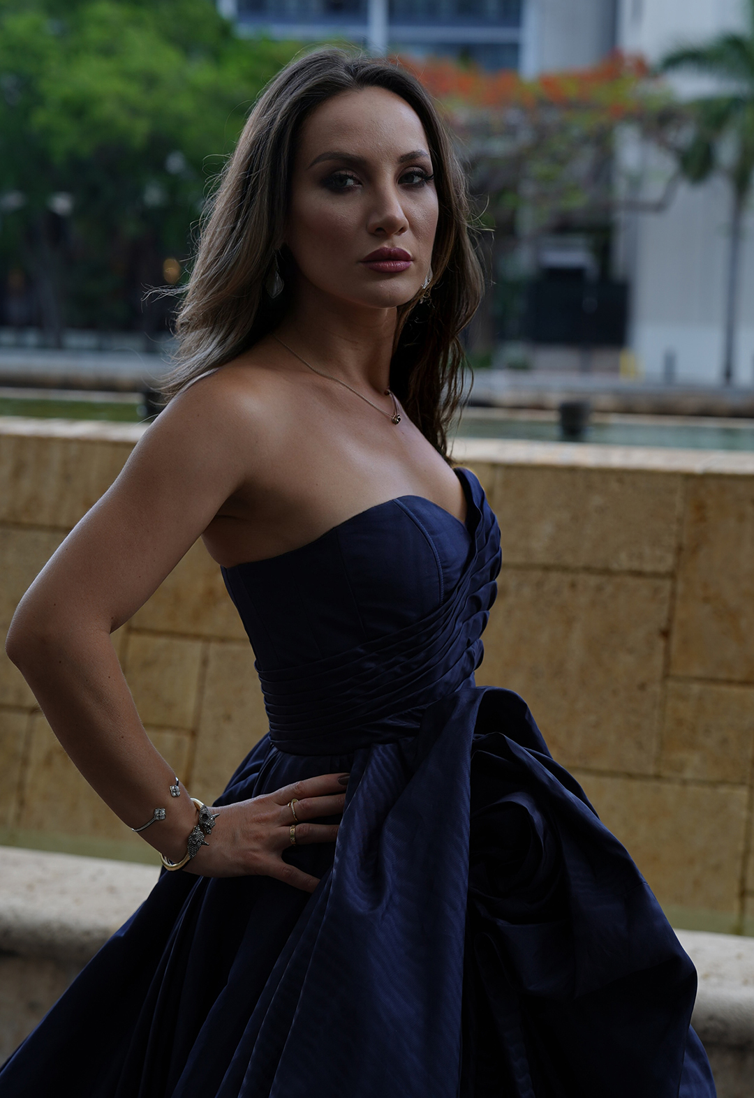 A close up shot of a model wearing a dark blue moire faille cowl skirt and fluted bodice gown.